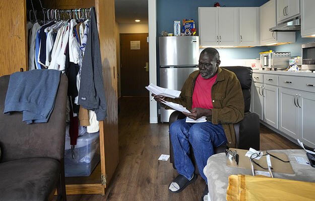 Army veteran Reggie Austin sits in his apartment looking at some paperwork at the newly-opened Tunnel to Towers Veterans Village