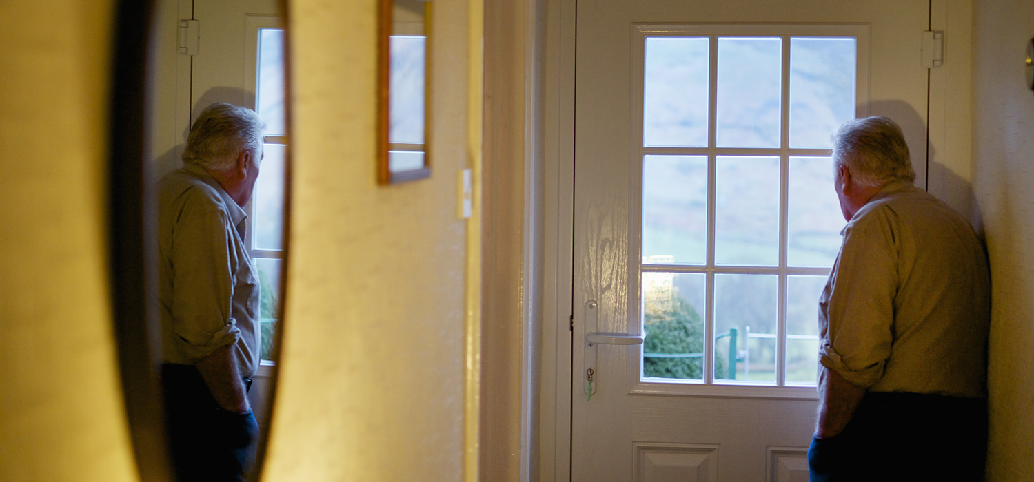 older man looks out window