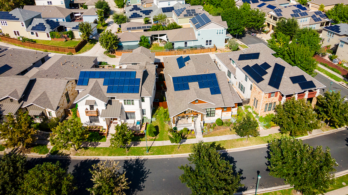 Aerial shot of large green neighborhood with homes with solar roof panels