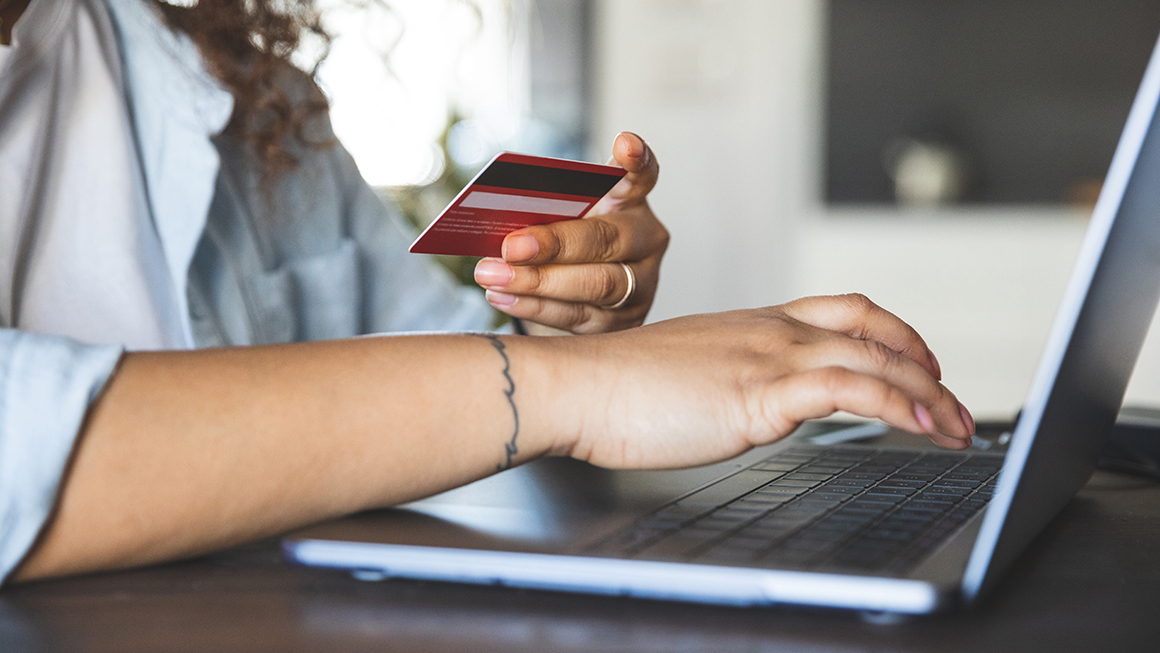 A woman using a laptop with her credit card in hand.