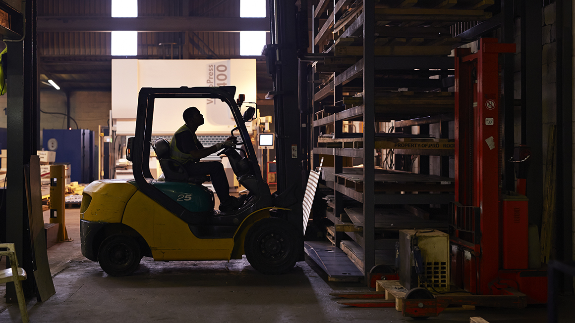 Employee operates lift in a warehouse