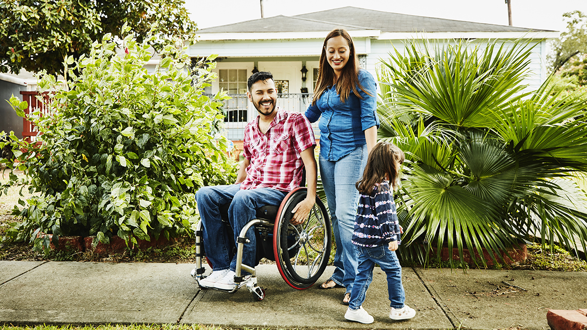 A man in a wheelchair with a woman and child.