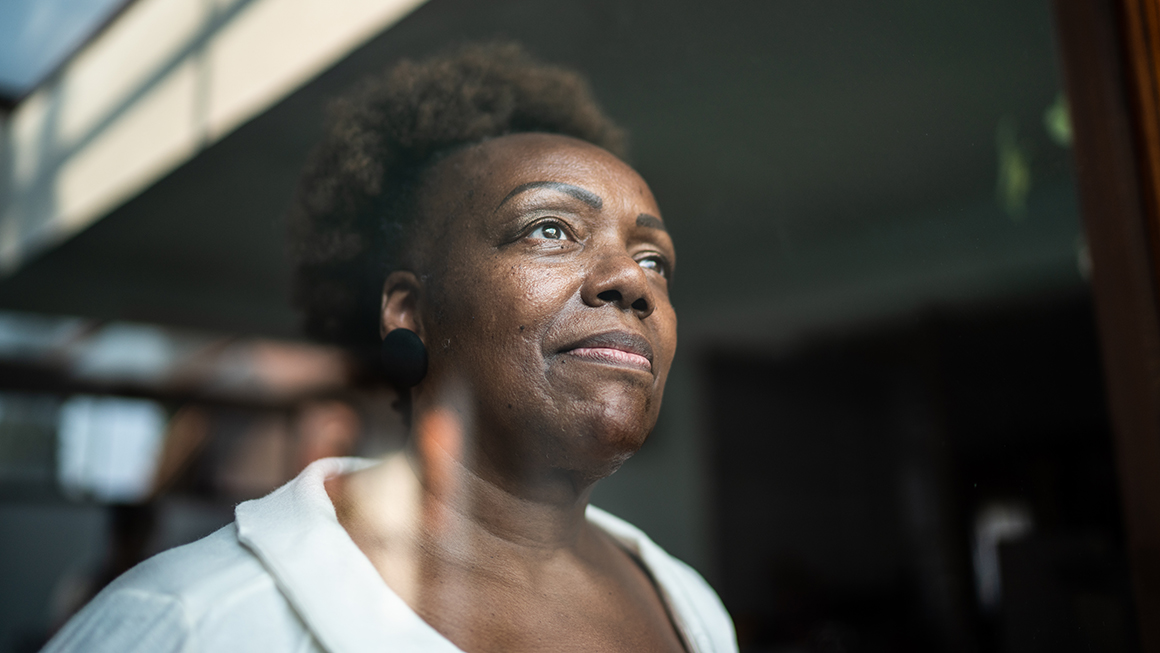 A Black woman looking a window. 
