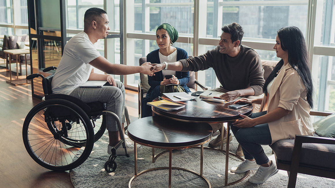 A man in a wheelchair meeting up with three more people. 