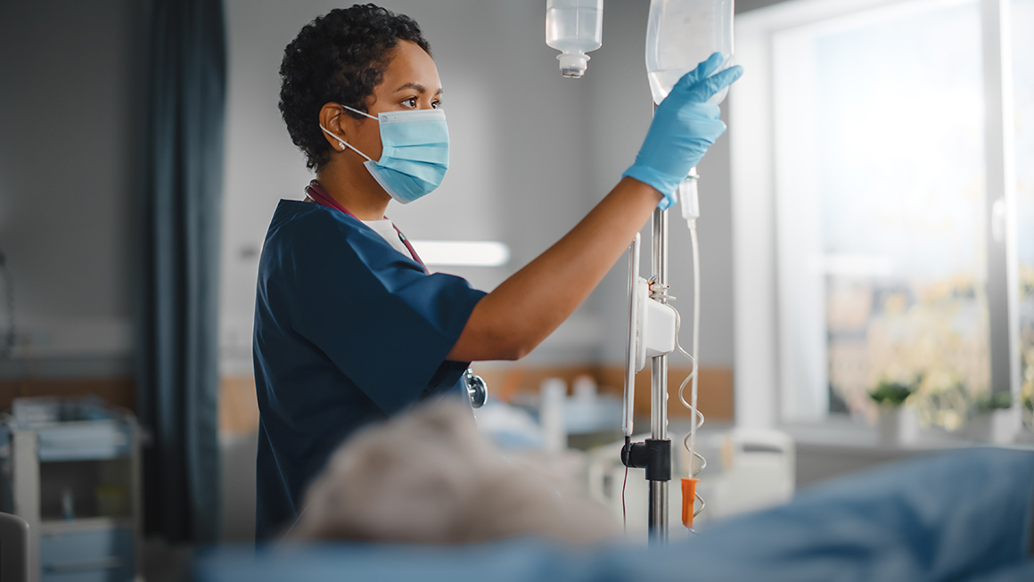 A nurse adjusting an IV bag. 