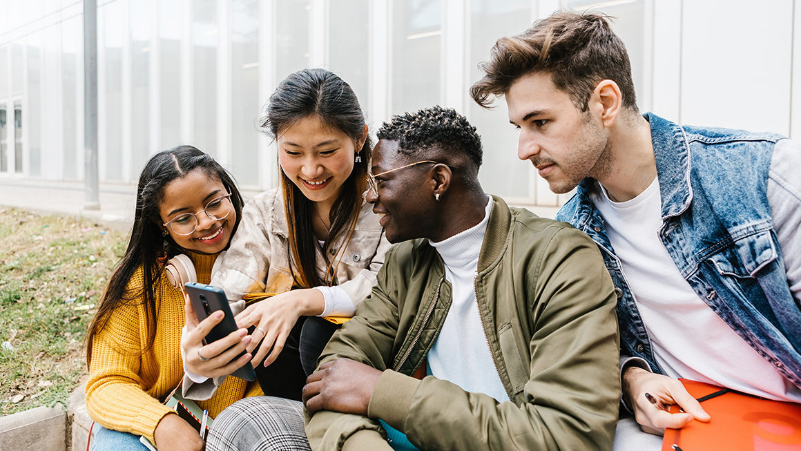 An image of a group of young adults looking at a cellphone. 