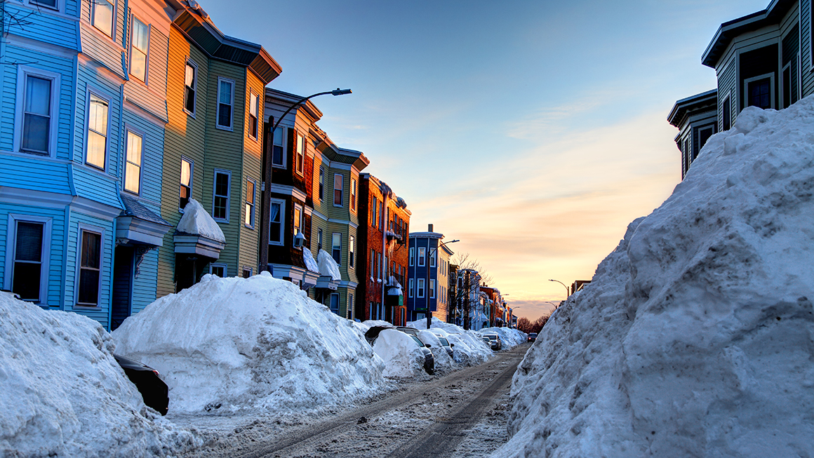 Row of townhomes with snow in the sidewalks. 
