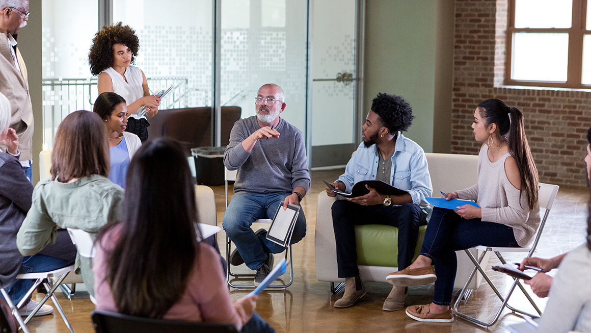 A group of people seated in chairs in a circle. 