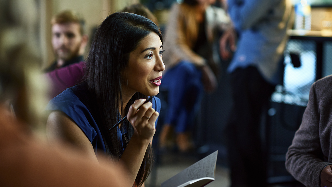 A woman taking with notebook and pen in hand.