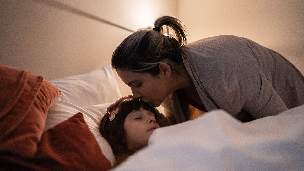 A women kissing her child on her forehead.