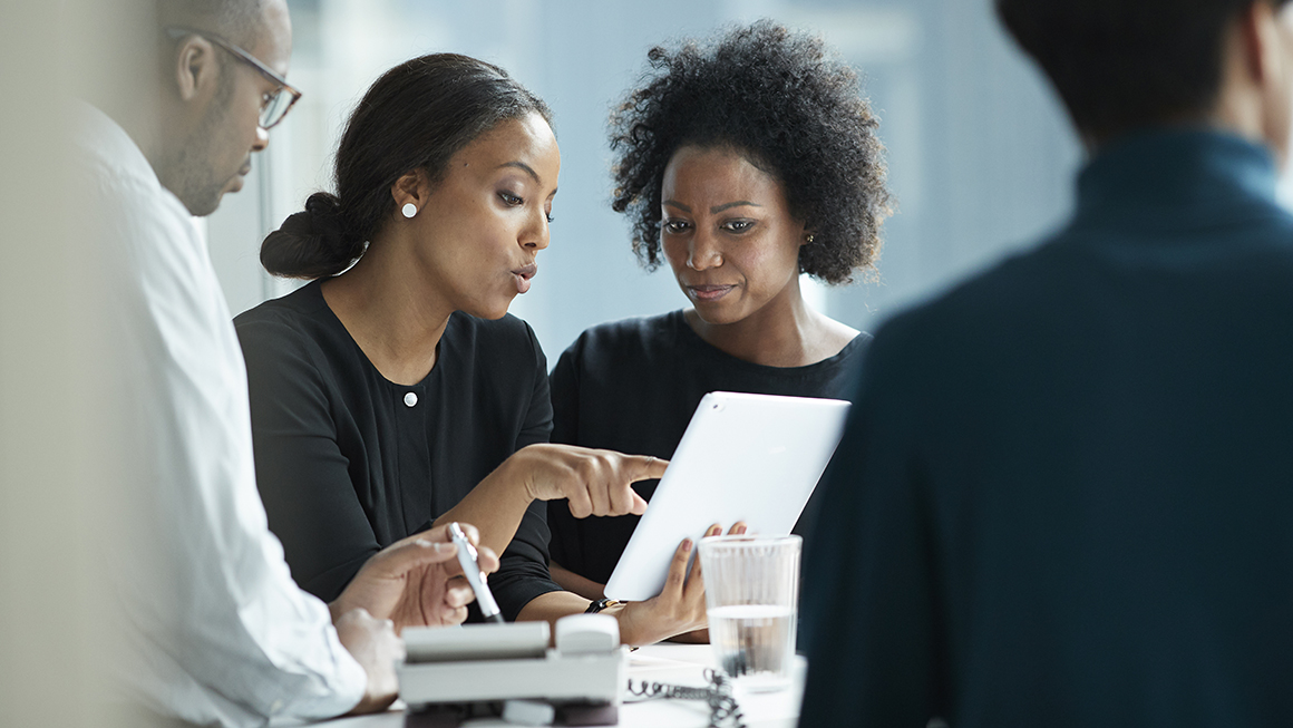 Two women working and looking at a tablet.