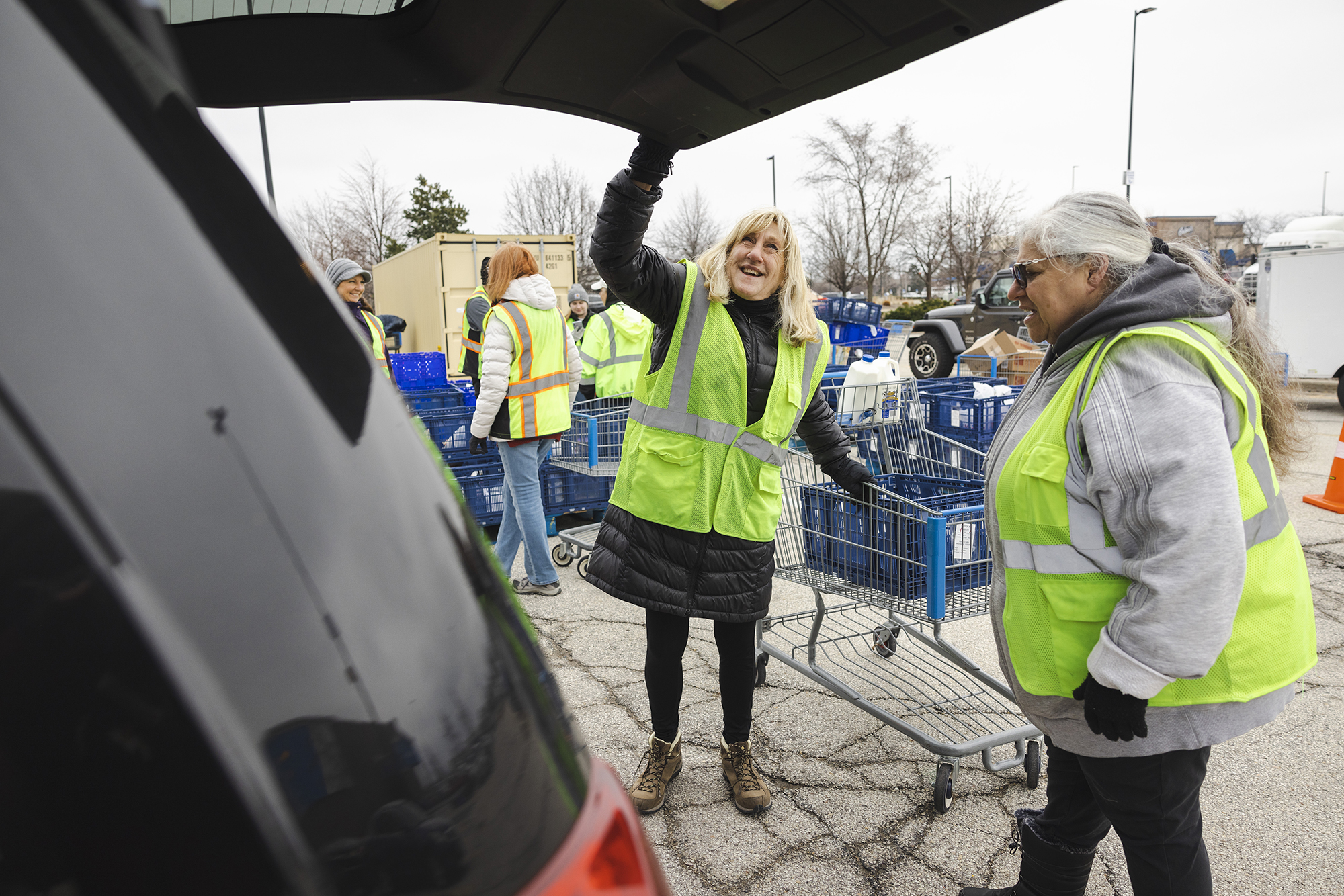 Two volunteers loading an order into the trunk of a car.