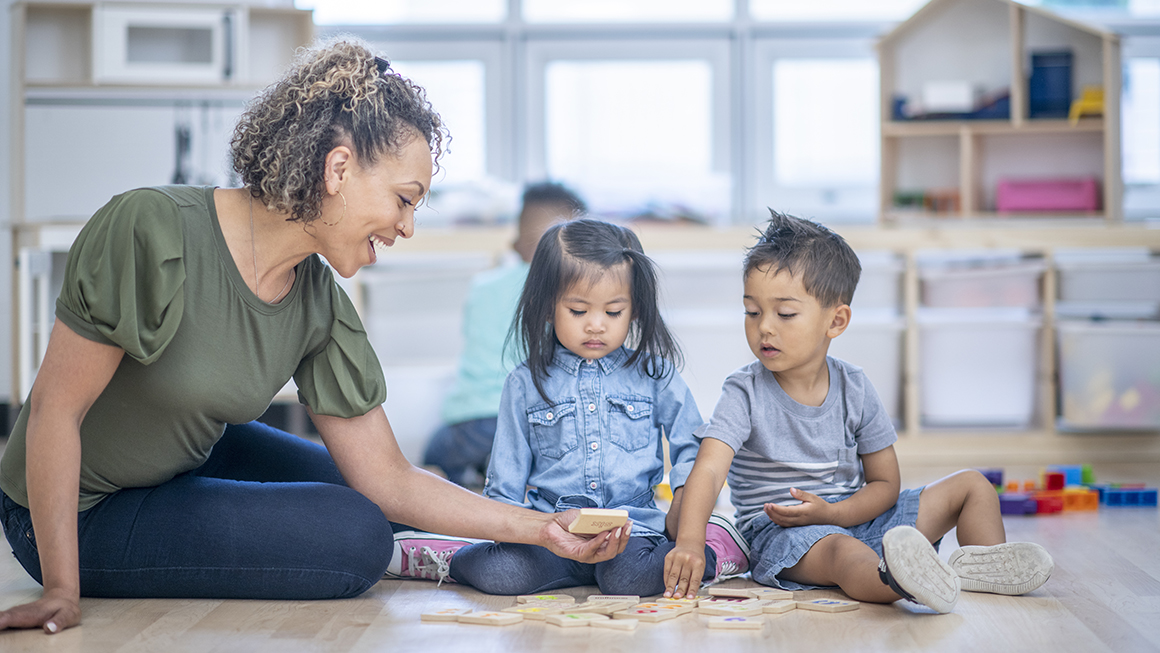 A teacher playing with yound children.