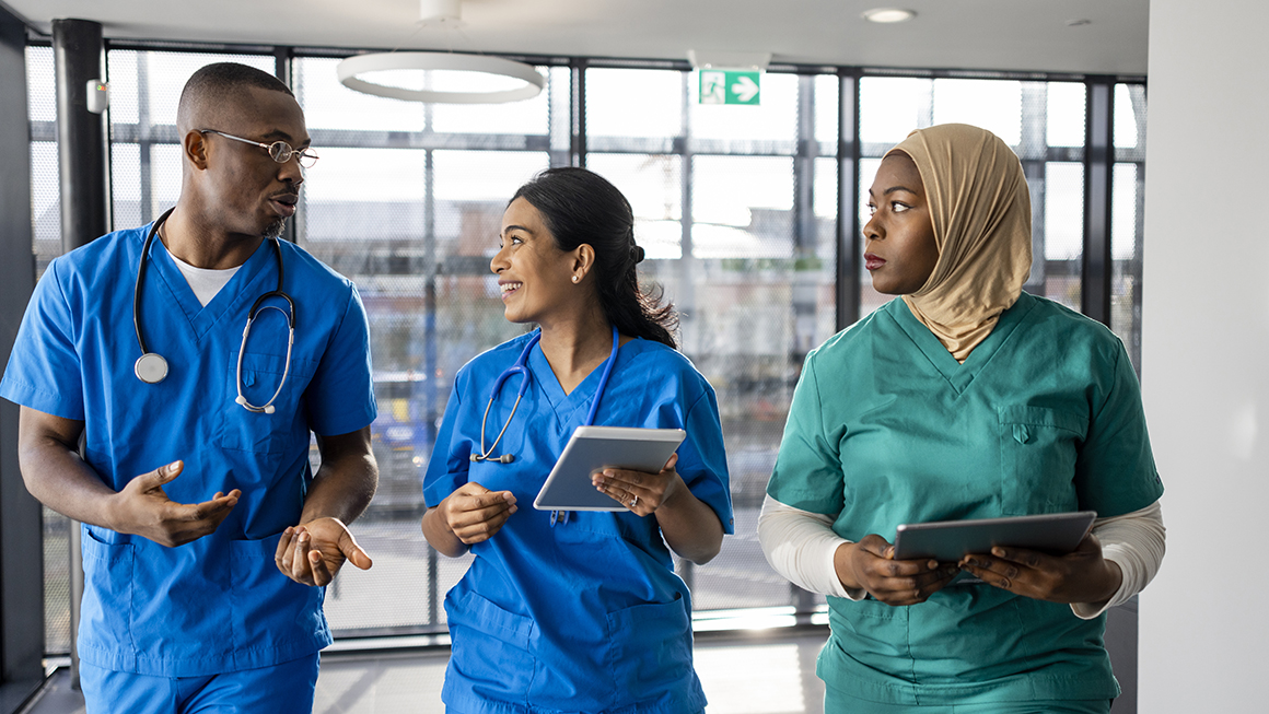 Three nurses walking down a hallway. 
