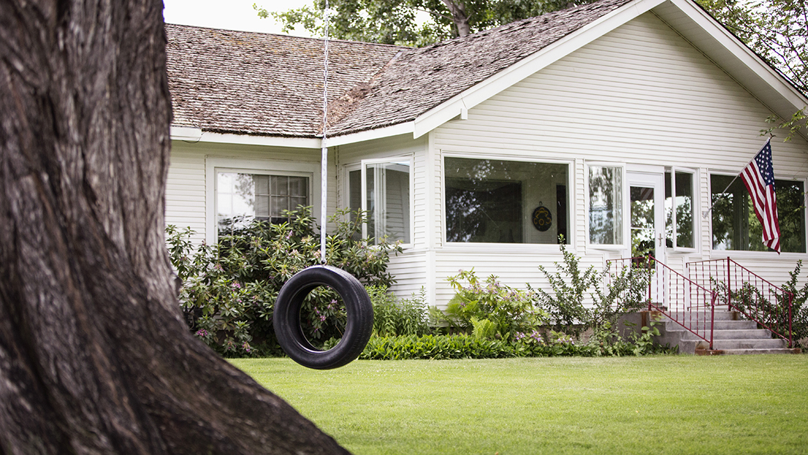 A single family home with a tire swing outside.