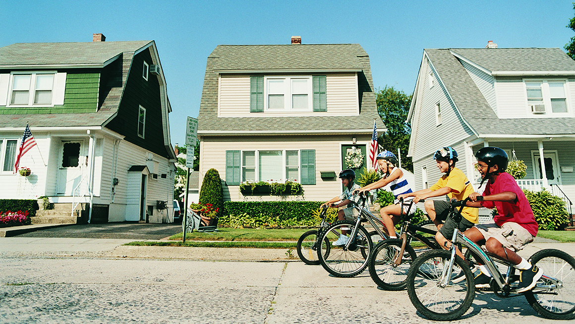 Children riding bikes in a neighborhood street.