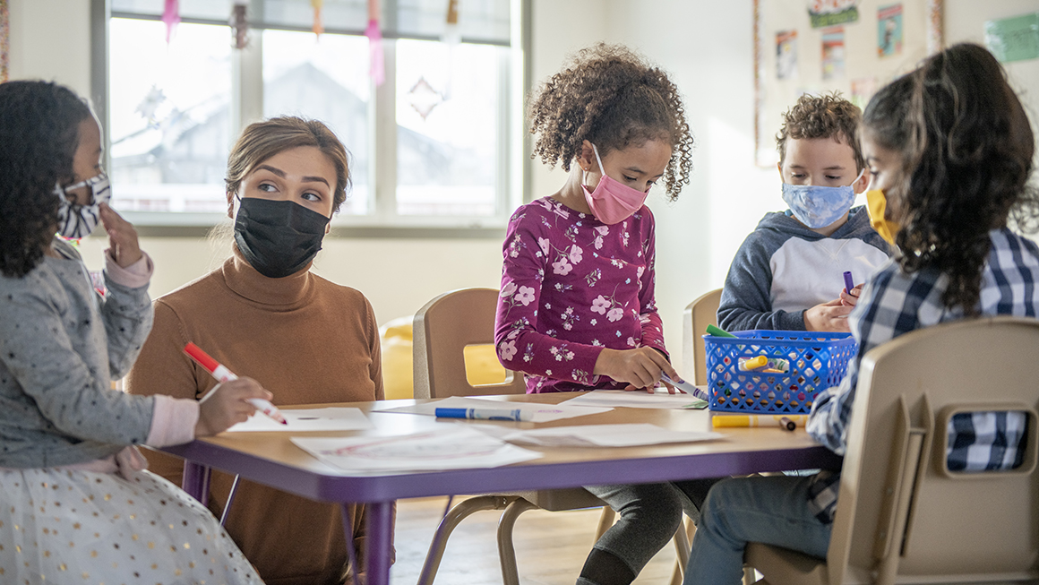 A table of school aged children around a desk. 