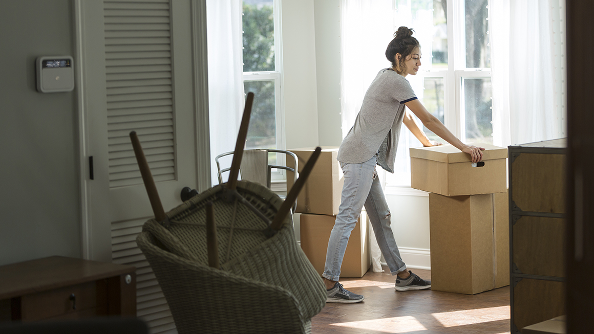 A woman in her home surrounded by moving boxes.