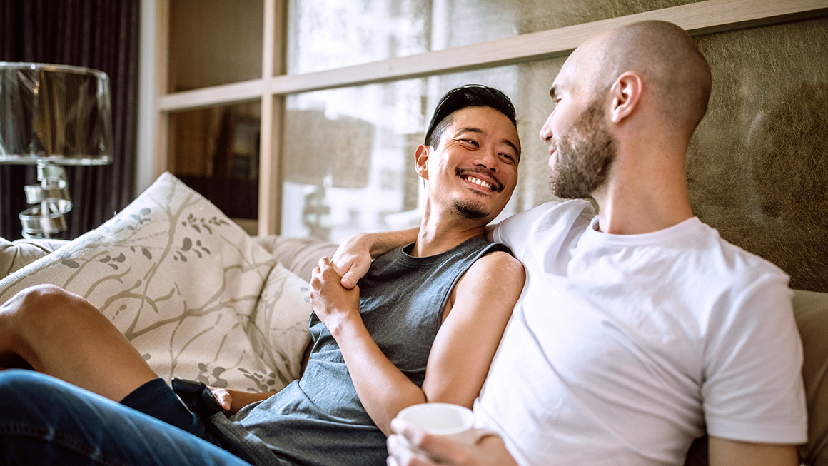 Two men hugging each other while they sit on a couch.