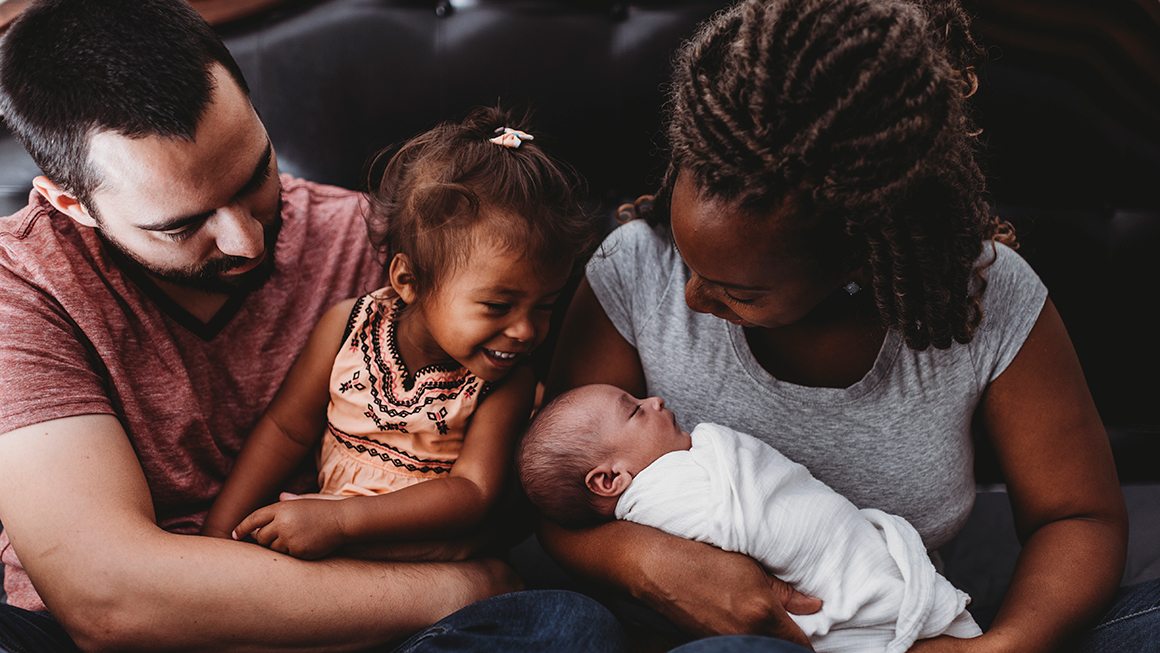 A man and women holding their two young children.