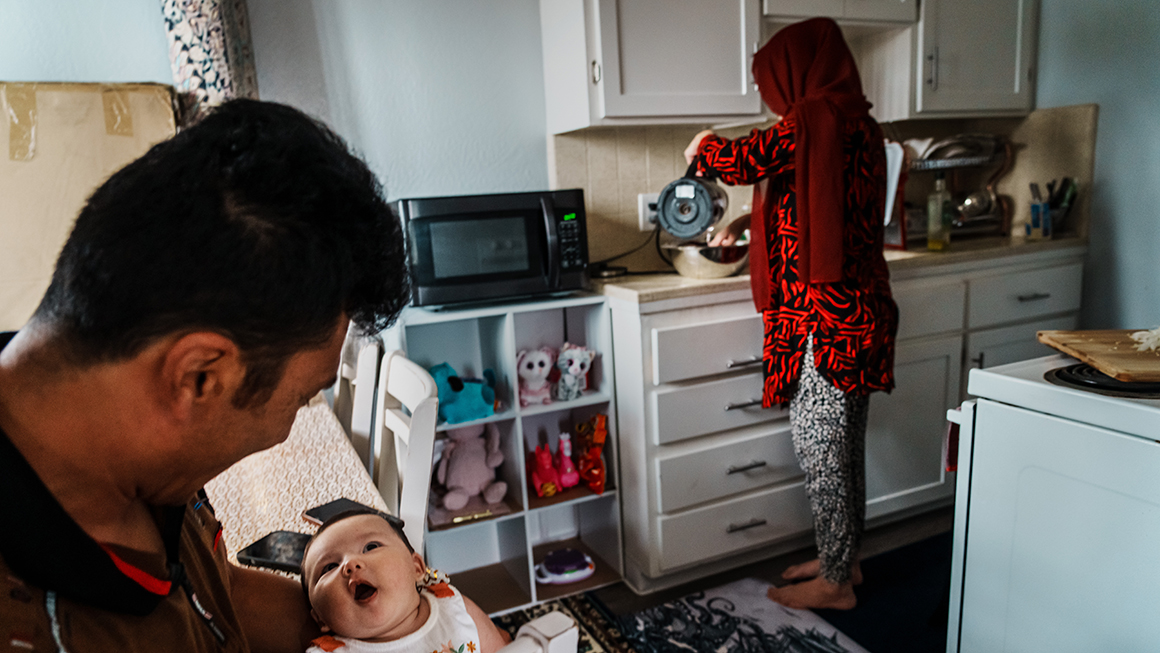 Two parents  in their home holding their baby.