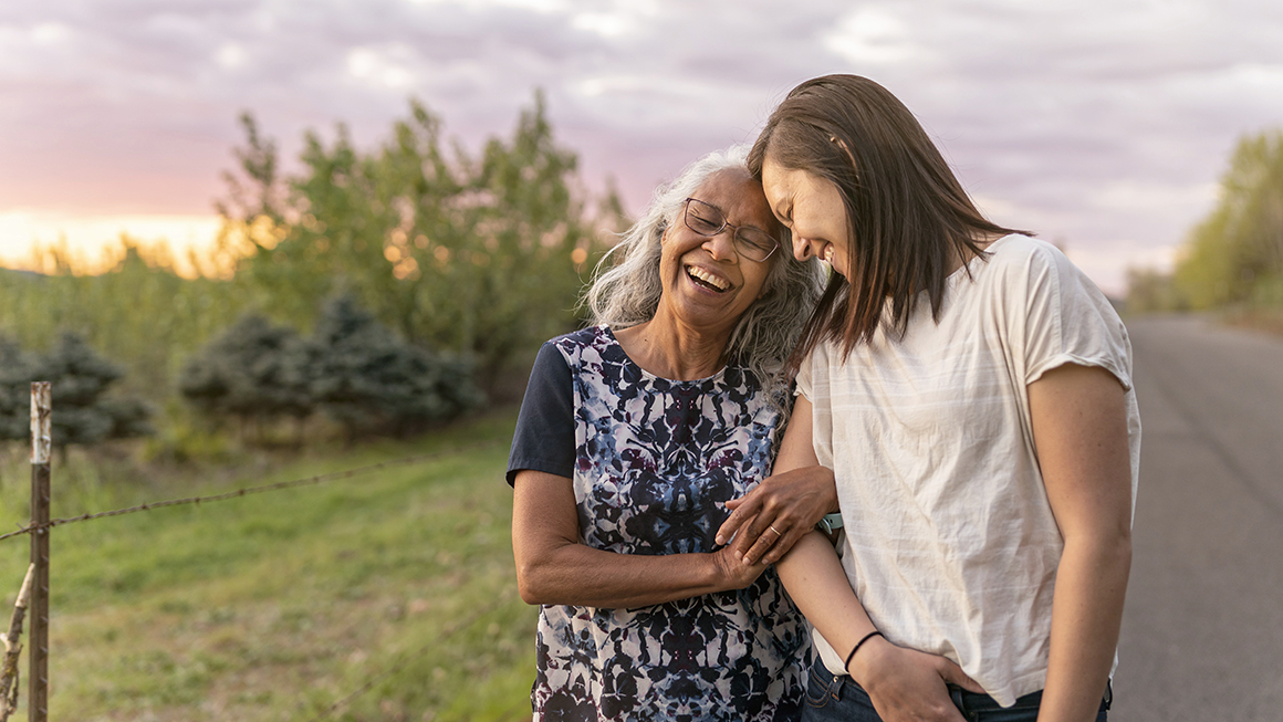 An older woman and her daughter walking outside.