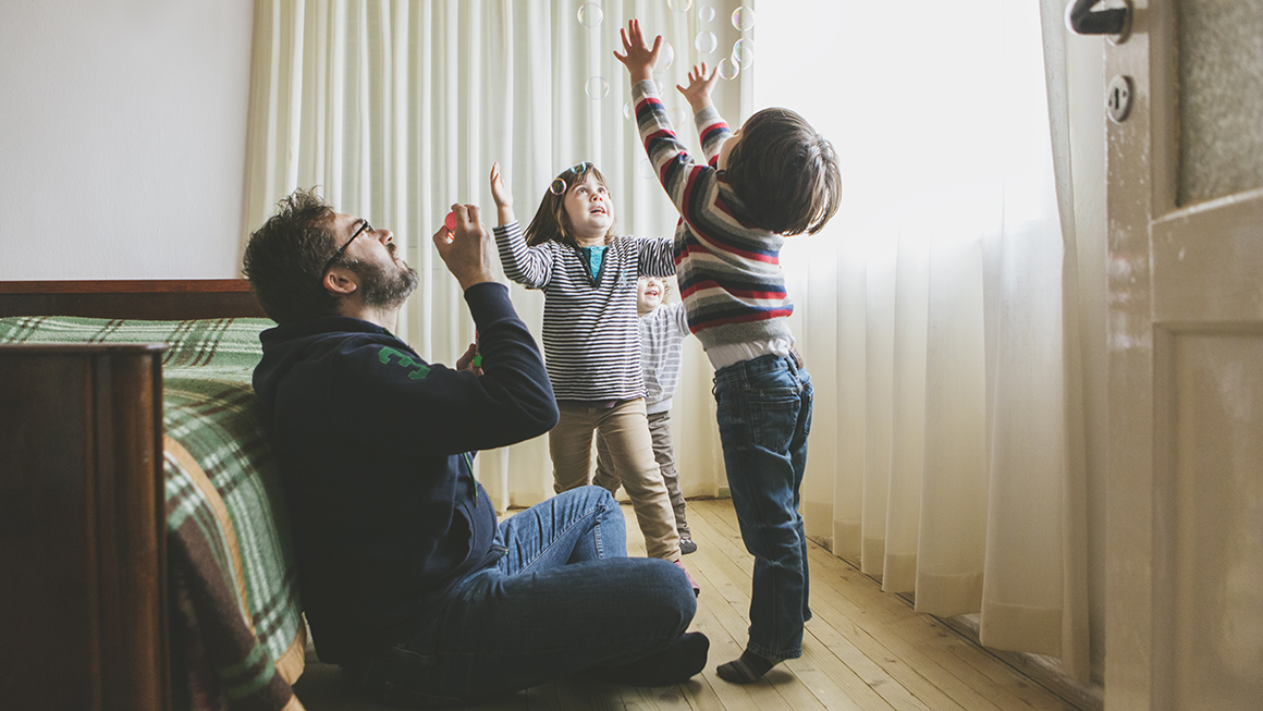 A father playing with his children in the bedroom.