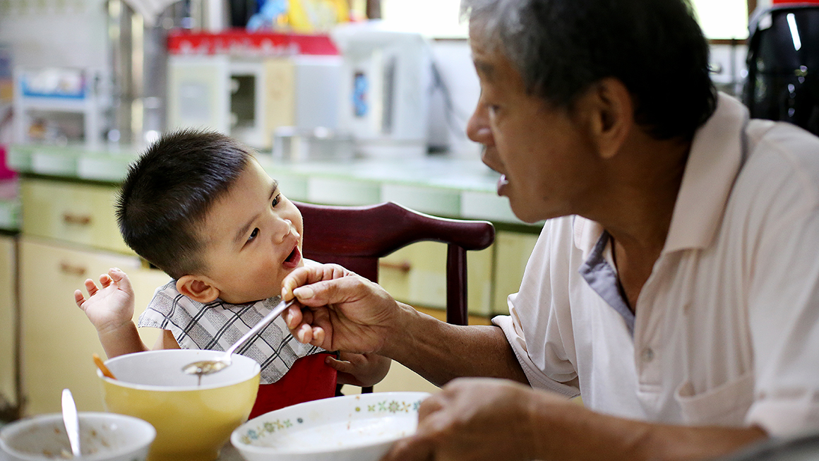 A dad feeding his son. 