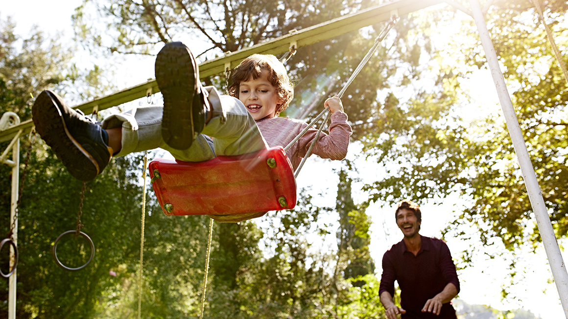 A father pushing his son on a swing.