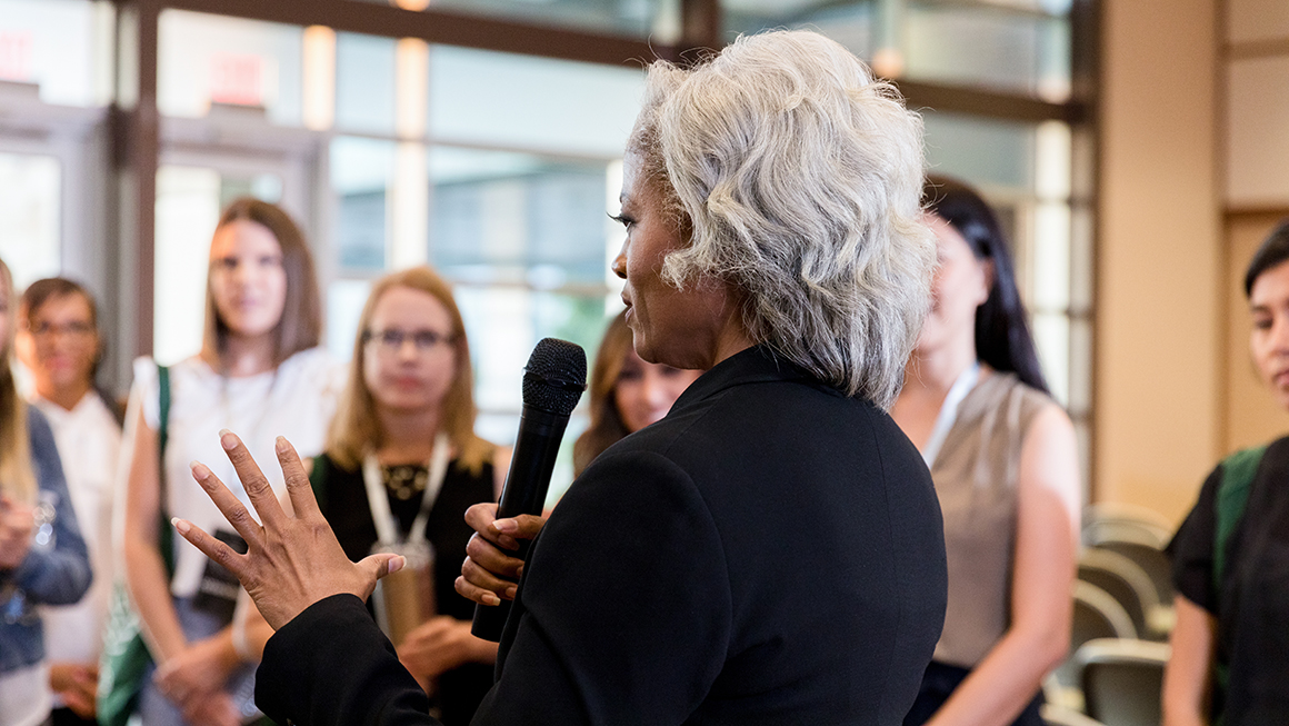 An older black woman speaking at an event.
