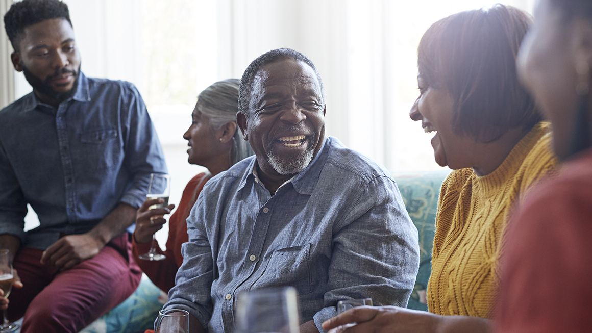 A black men laughing among a group of people.
