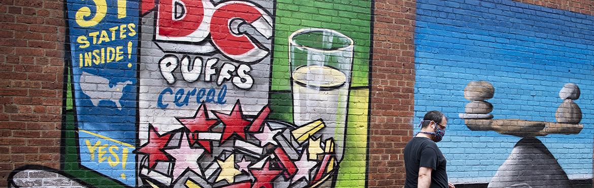 A man walks by new murals depicting different interpretations of DC statehood.