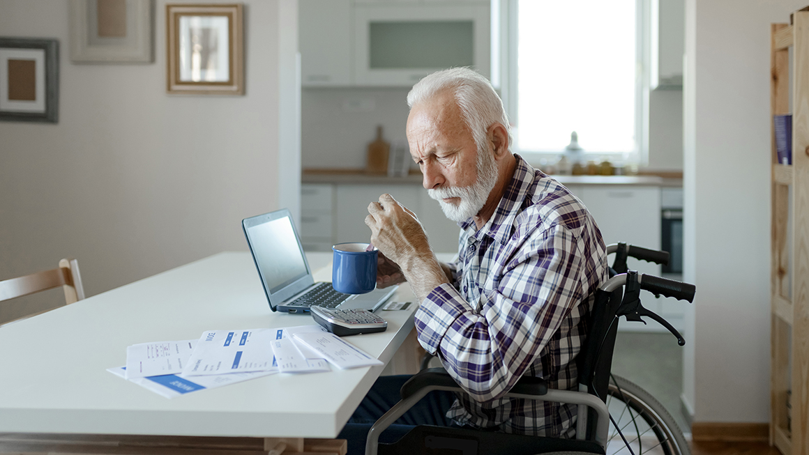 An older man in a wheelchair looking over bills.