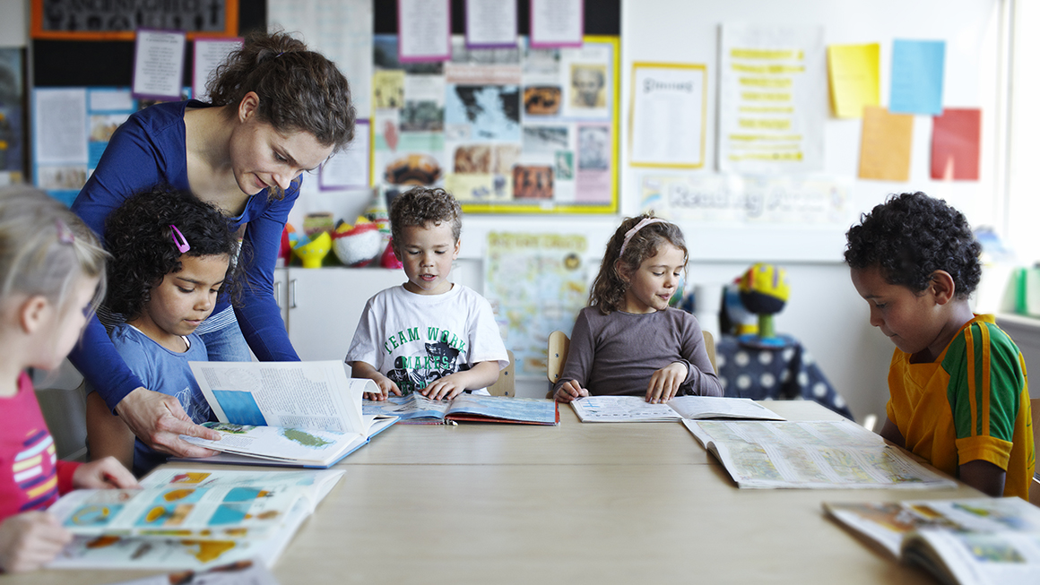 Teacher looking at books with children