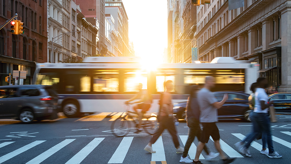 People walking at a cross walk in a city.