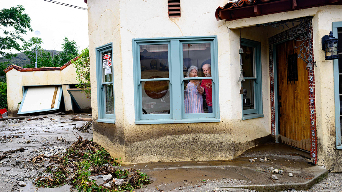 Residents trapped in their home peer out a window while waiting for help in Yucaipa, California.