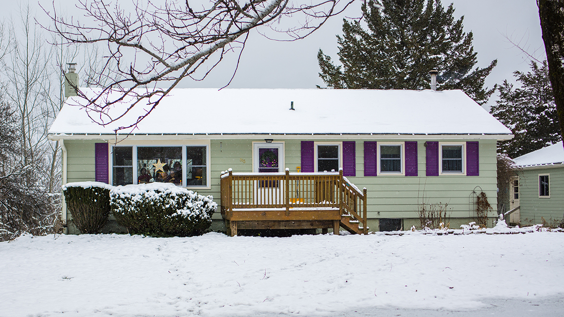 The front of a single family home with snow on the ground.