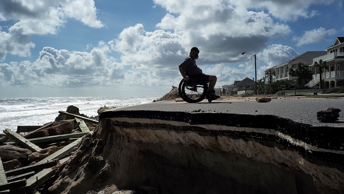 A man in a wheelchair near a beach.