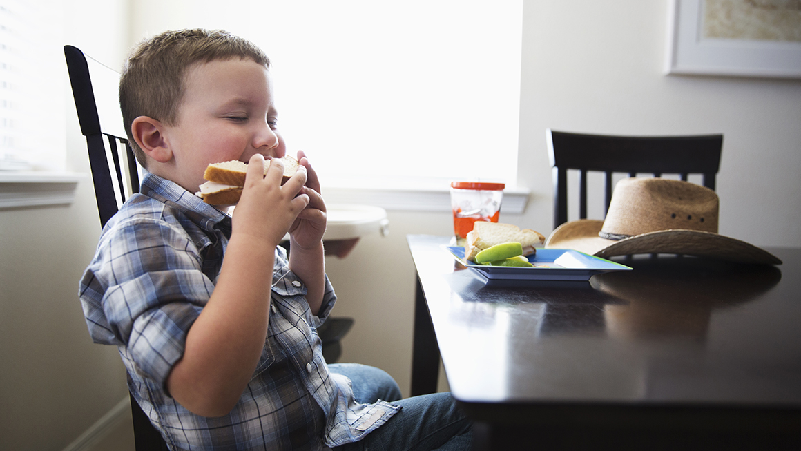 Child eating a sandwich at home.