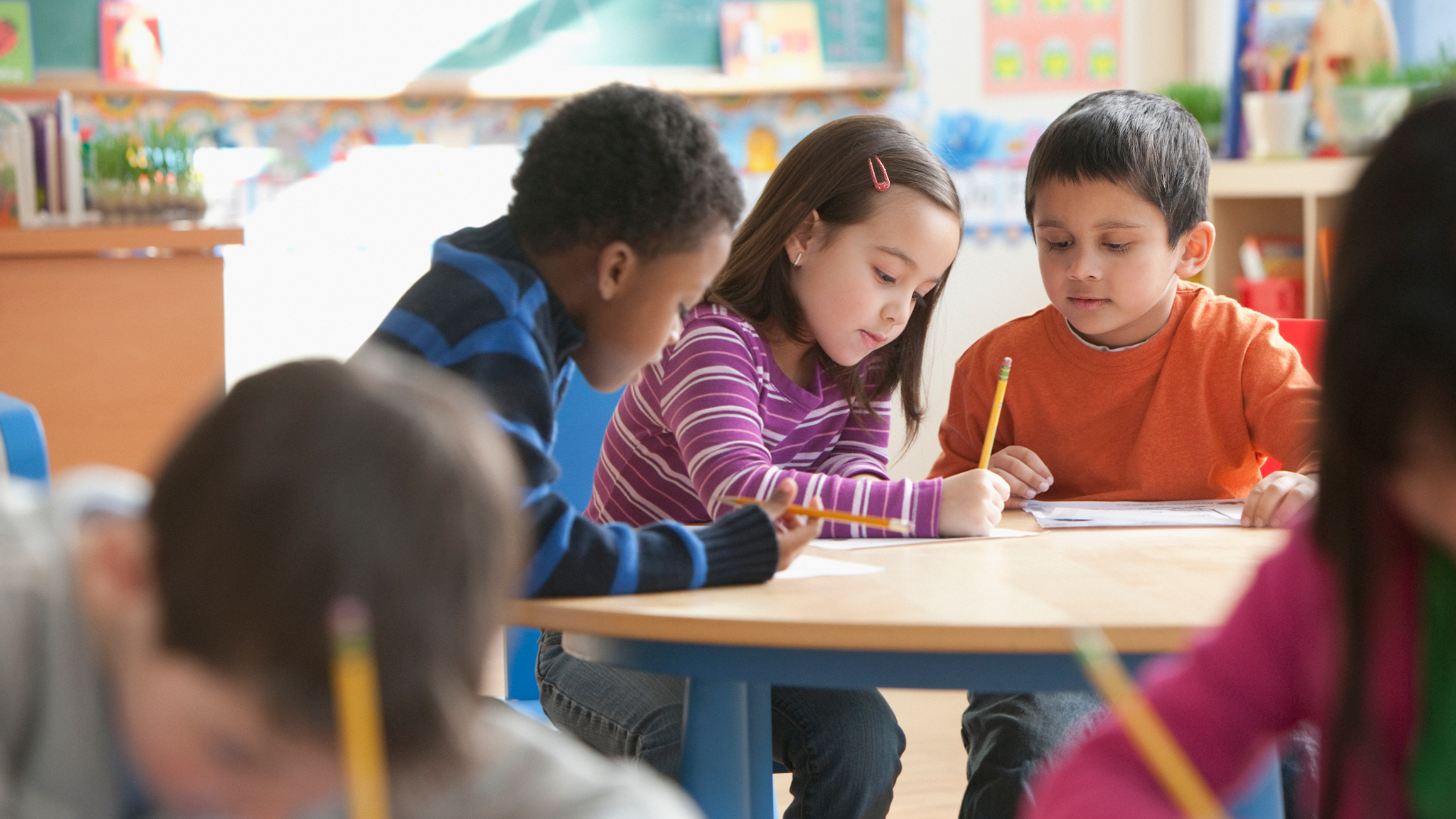 school aged children at their desks working on school work.