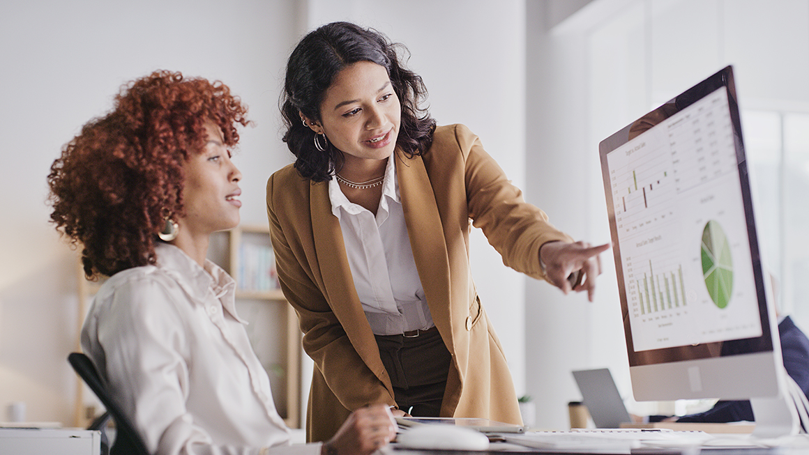 Two women at work looking at a desktop screen.