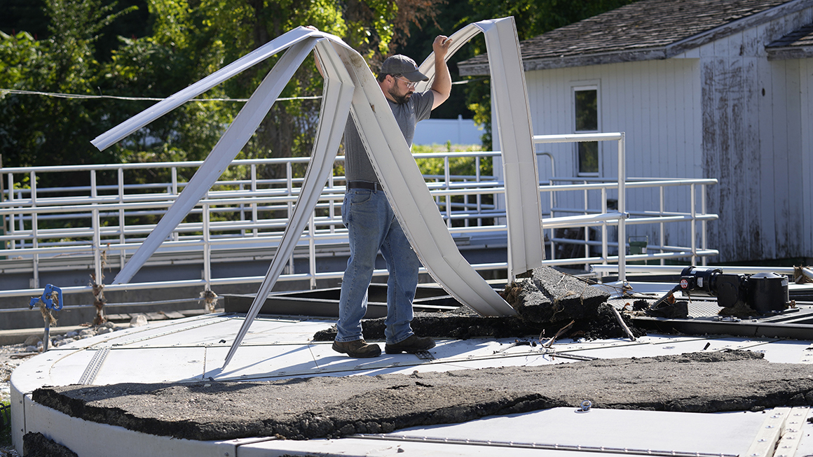 Elijah Lemieux, of the Vermont Rural Water Association, cleans up debris that was left by rising waters over the wastewater clarifier at the treatment plant following July flooding.