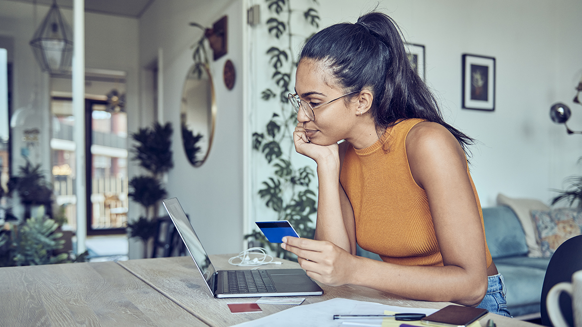 A young woman looking at a laptop in her home.
