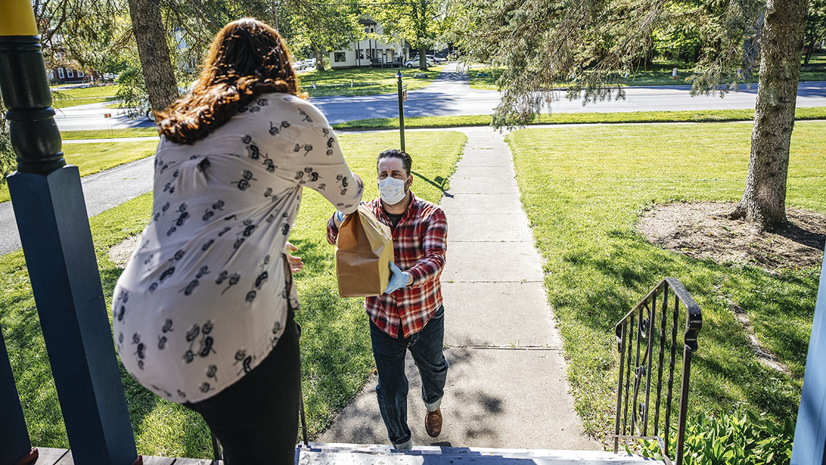 A woman receiving a food delivery at her front door.