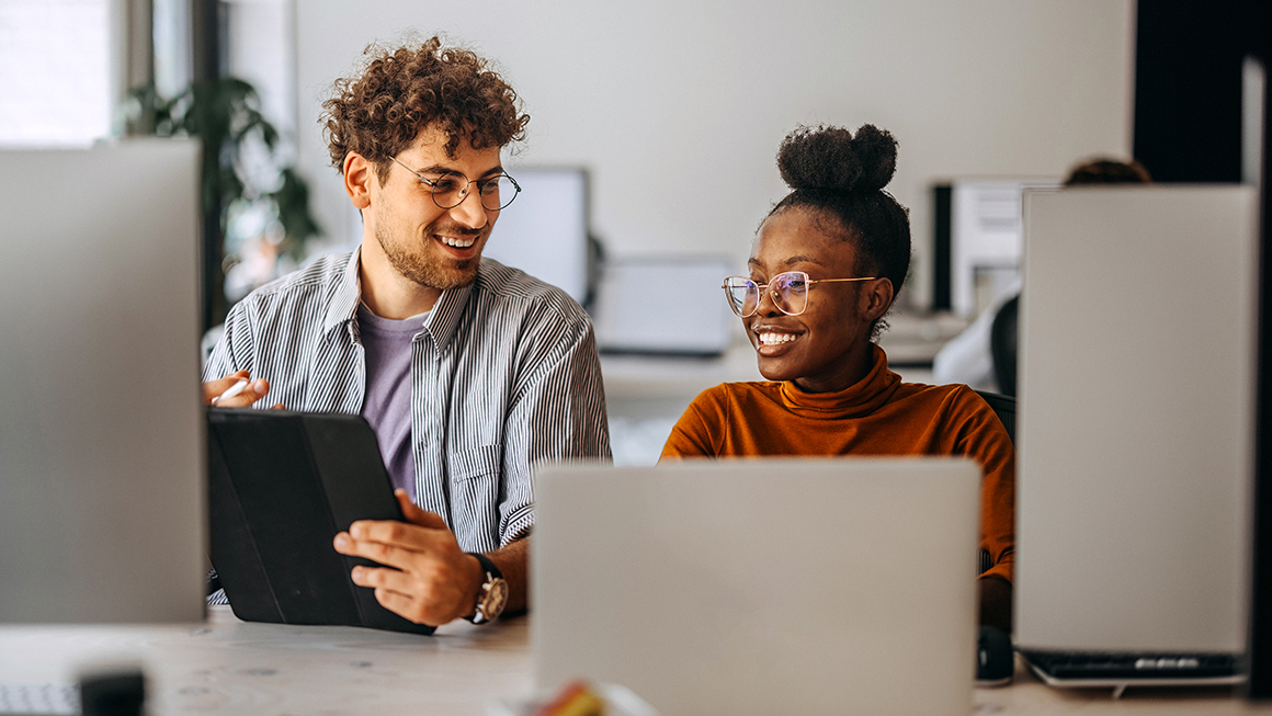 Two people in front of desktop computers.