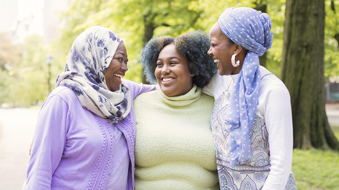 A group of black women of different ages hugging outside.