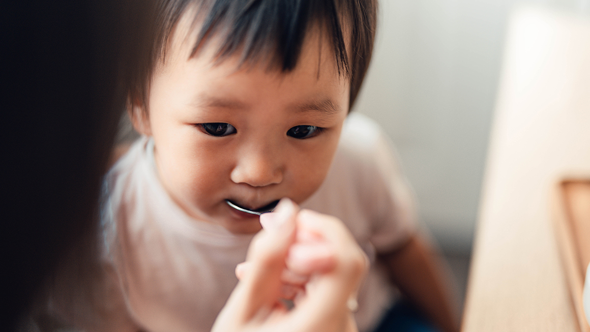 photo of baby being fed by spoon