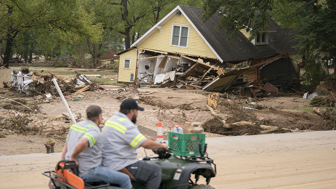Men on a four wheeler pass a storm-damaged house along Mill Creek in the aftermath of Hurricane Helene on September 30, 2024, in Old Fort, North Carolina.