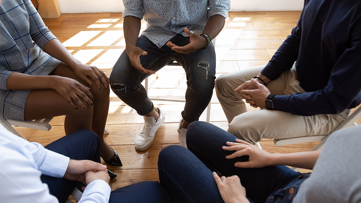 photo of people seated in circle talking share problems tell stories