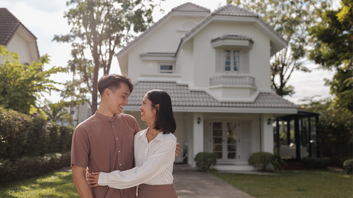 A couple hugging each other outside a single family home. 